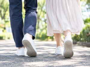 木漏れ日の小道を歩く二人の足元