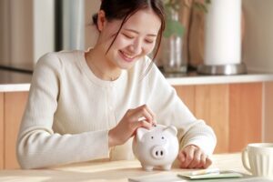 写真：ぶたさん貯金箱、節約や資産形成を楽しむ若い女性