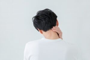 画像：首をおさえる男性のうしろ姿