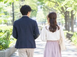 木漏れ日の並木道を歩く二人の後ろ姿