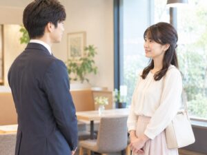 カフェラウンジで向かい合って挨拶をする男女