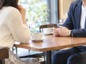 カフェの窓辺で向き合って話す男女