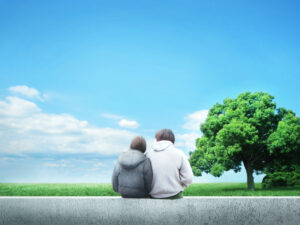 景色の良い公園で並んで座るカップルの後ろ姿