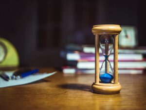 青い砂の砂時計とテーブルの上に積まれた本