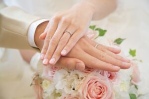 画像:ブーケの上に指輪交換した二人の手