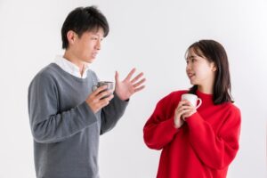 画像：マグカップを持って会話する男女