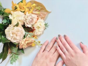 花束と結婚指輪をはめたカップルの手