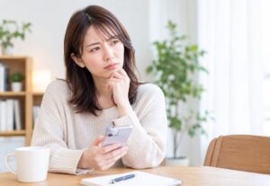 スマートフォンを手に悩む女性